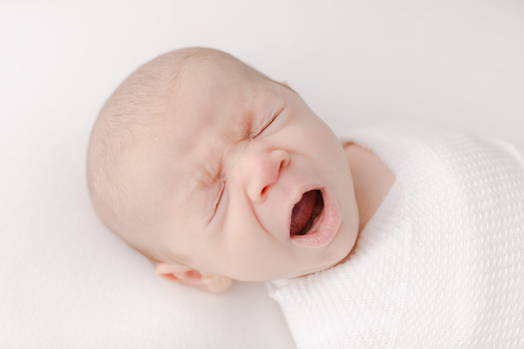 newborn baby swaddled and yawning