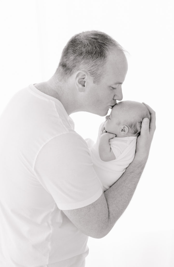 photograph of dad kissing newborn on forehead