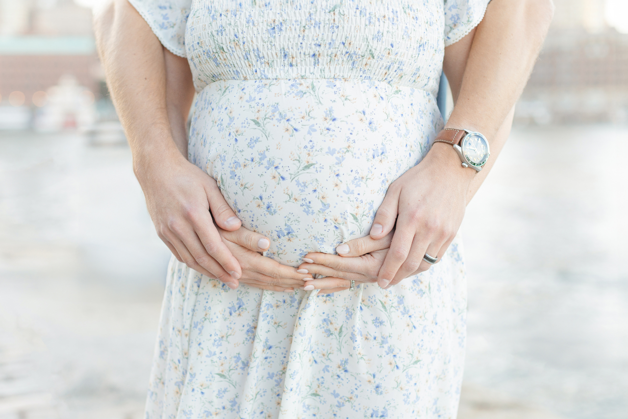 close up image of woman's baby bump and hands showcasing importance of boston prenatal massage