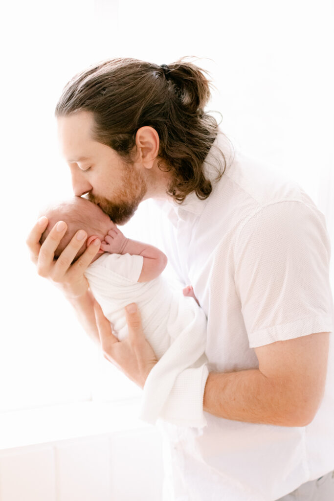 new dad gently kisses daughter on forehead