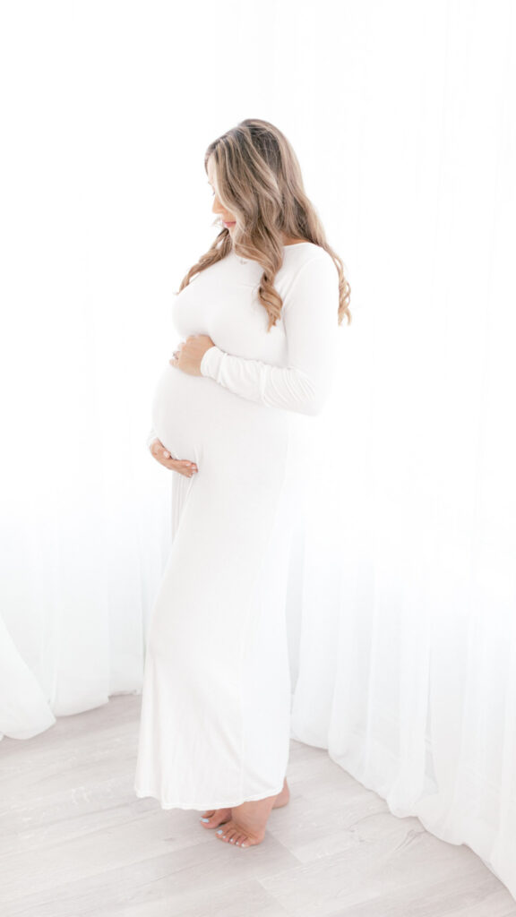 expecting mom looks down at her baby bump during studio photoshoot