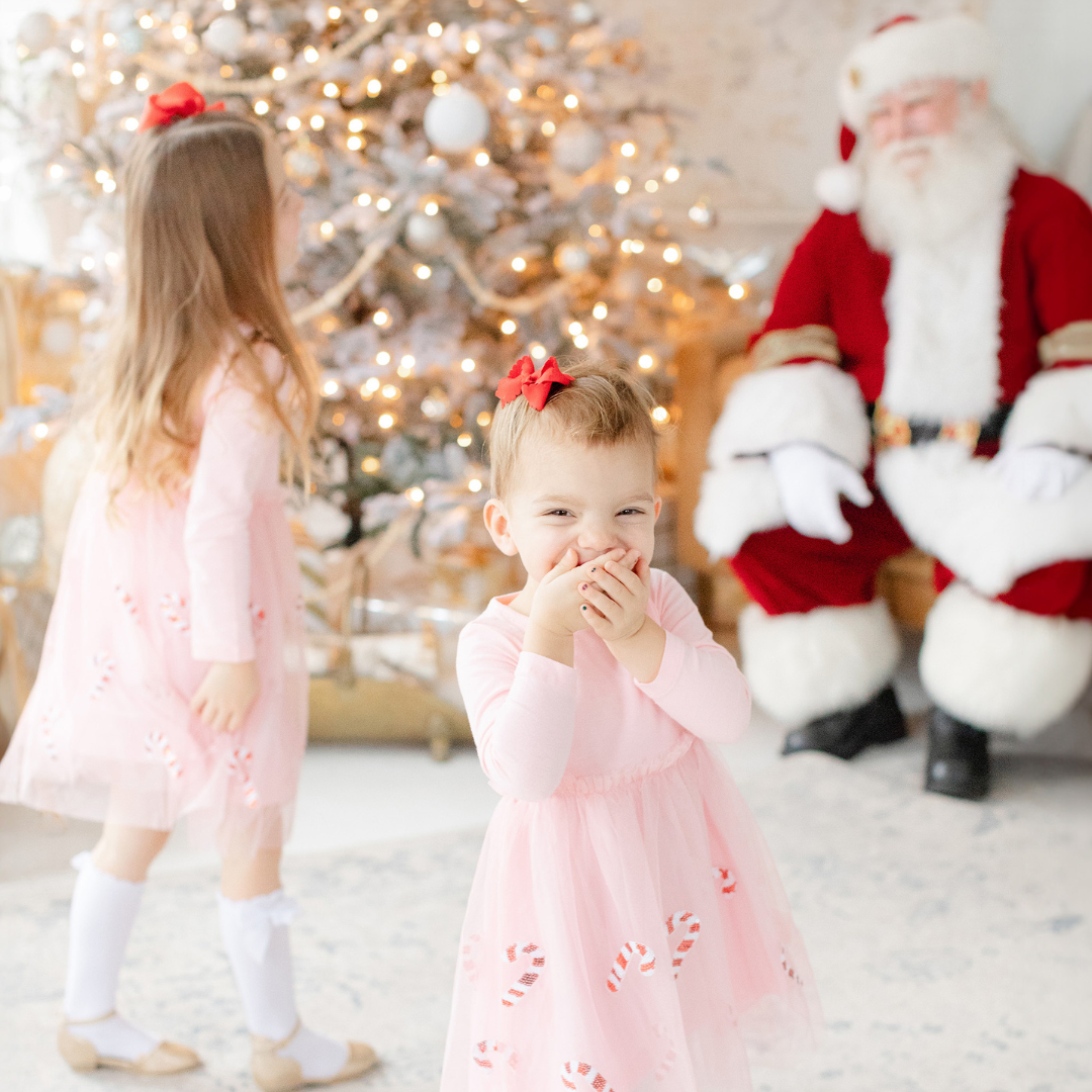 young girl looks at camera with surprise upon meeting Santa Claus for the first time during a Boston photoshoot