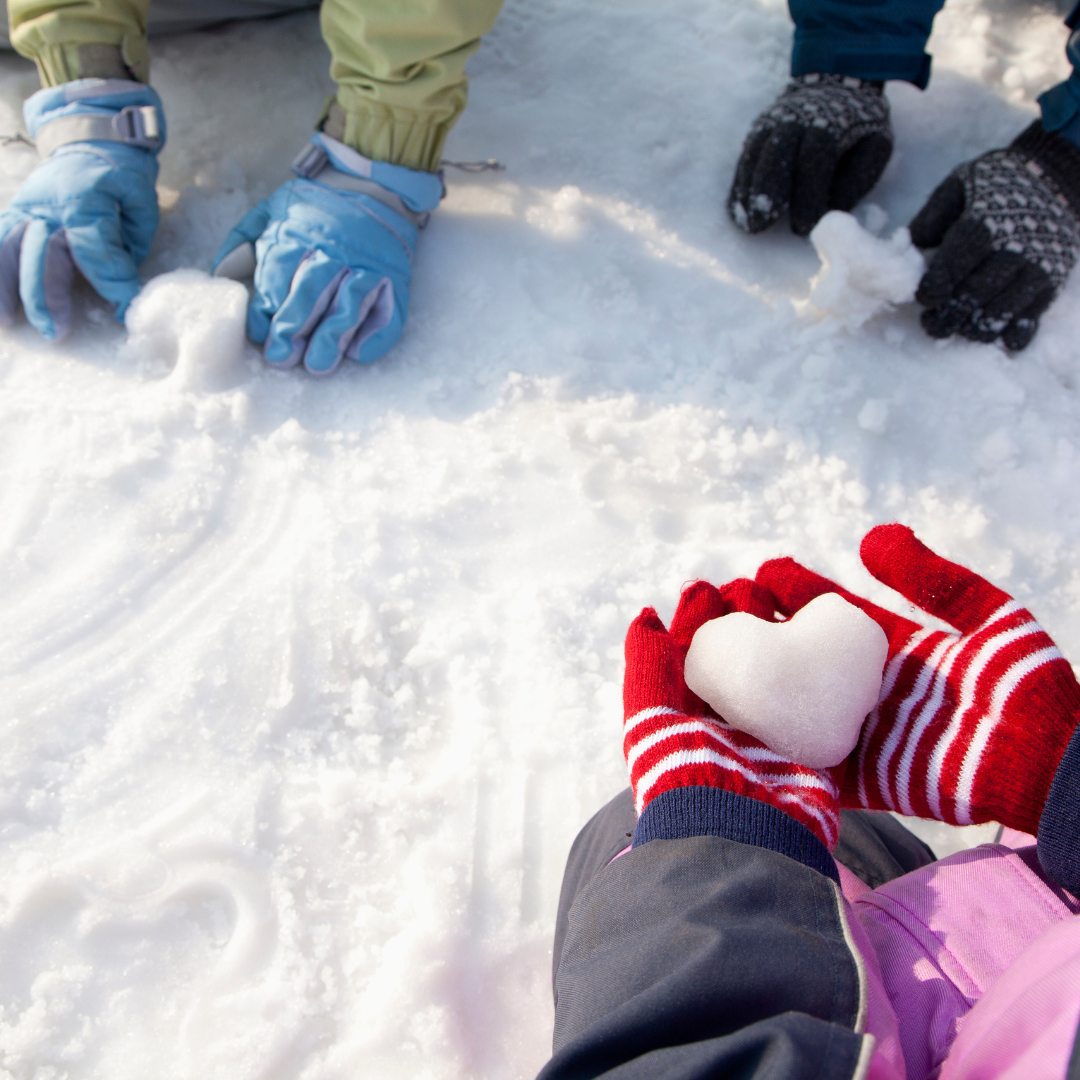 close up image of child's hands wearing mittens and holding snow