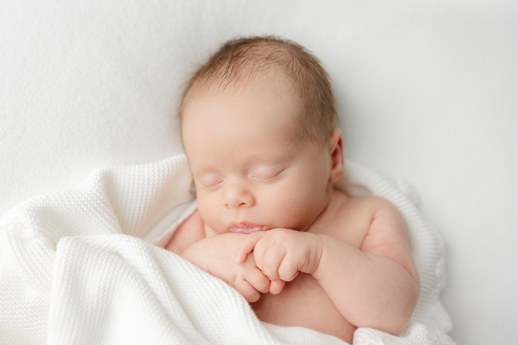 Sleeping newborn wrapped in a soft white blanket during a relaxed in home framingham newborn photography session